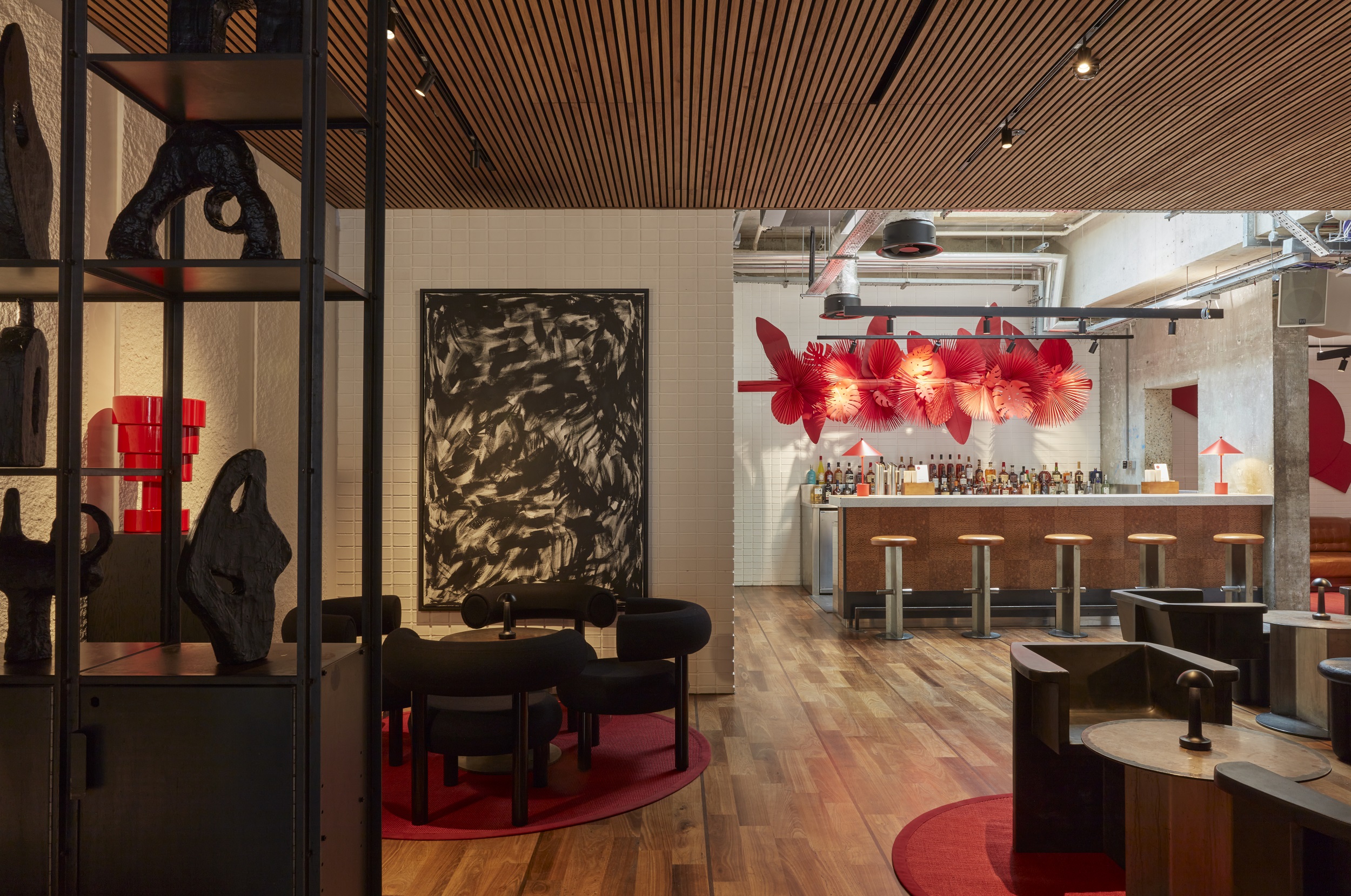 A contemporary bar featuring striking red and black artwork adorning the walls, creating a vibrant atmosphere.